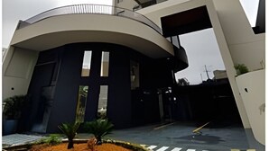 A modern building with a curved entrance and a tall structure with balconies. - Casa Confortavel em Foz do Iguaçu (Foz do Iguaçu)