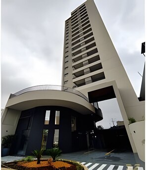 Un edificio moderno con una entrada curva y una estructura alta con balcones.