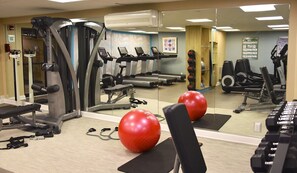 A gym with treadmills, elliptical machines, and red exercise balls.