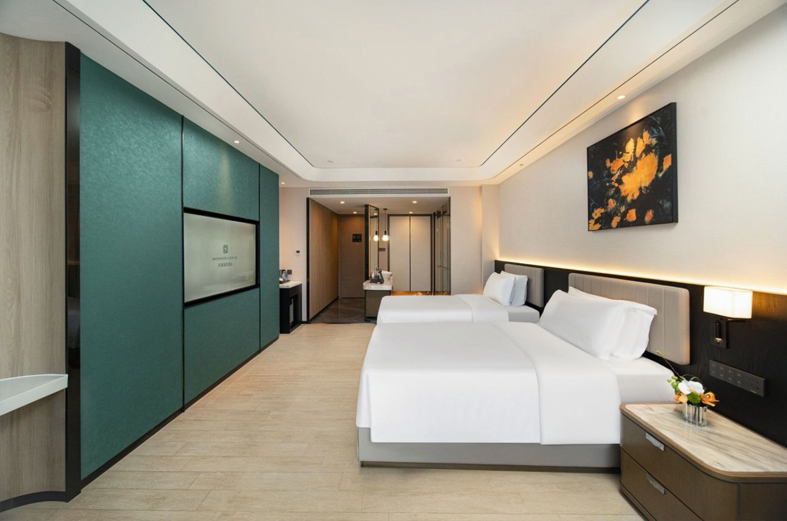 Quarto de hotel com cama, mesas de cabeceira, televisão e um quadro na parede.