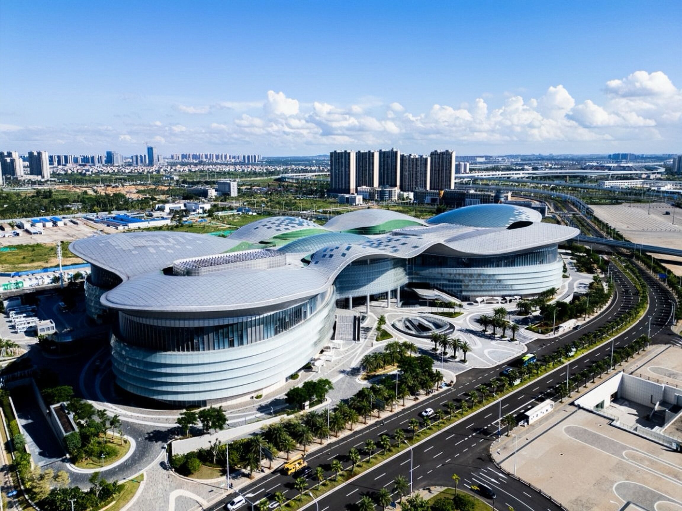 A modern architectural building with curved structures and a surrounding road network.