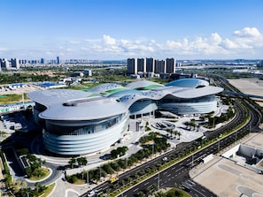 A modern architectural building with curved structures and a surrounding road network.