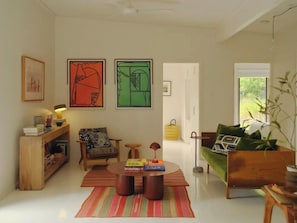 Ein Wohnzimmer mit Sofa, Sessel, Couchtisch und Bildern an den Wänden.
