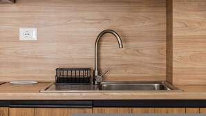 Una cucina moderna con lavello in acciaio inox, piano di lavoro in legno e portautensili nero.