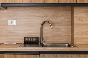 A modern kitchen with a stainless steel sink, wooden countertop, and a black utensil holder. - Central Quiet Tirana Flat 1BR Apartment (Tirana)