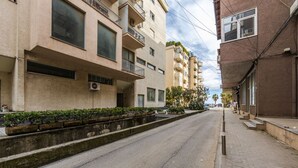 A street with multi-story buildings, a sidewalk, and a median with plants. - Sunset Apartment 1BR Escape (Durrës)