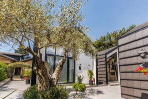 A modern building with a glass facade, a tree in the courtyard, and a door marked with the number 7. - Muraga Villas 7 Kupola (Dajt)