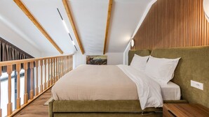 A bedroom with a bed, wooden ceiling beams, a wooden railing, and a painting on the wall. - Muraga Villas 7 Kupola (Dajt)