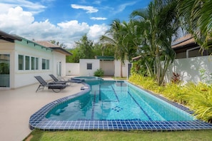 A swimming pool with tiled edges, lounge chairs, and palm trees. - Orchid Paradise Homes OPV307 (Tambon Hin Lek Fai)