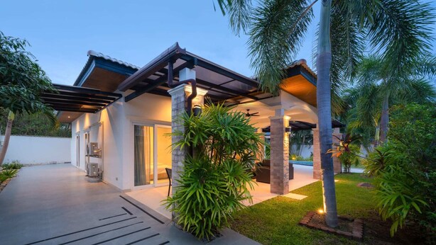 A modern house with a covered patio, a garage, and a well-maintained lawn. - Orchid Paradise Homes OPV307 (Tambon Hin Lek Fai)