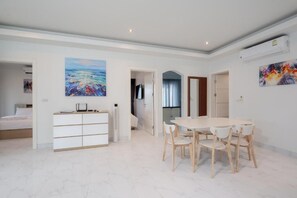 A modern living room with a dining area, white walls, and a large painting. - Orchid Paradise Homes OPV307 (Tambon Hin Lek Fai)