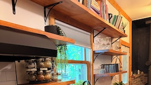 A kitchen with a wooden countertop, a gas stove, a sink, and shelves with books and kitchenware. - The Schoolhouse Cabin - 2BR, 1.5BA with Hot Tub and Game Room (Hudson)