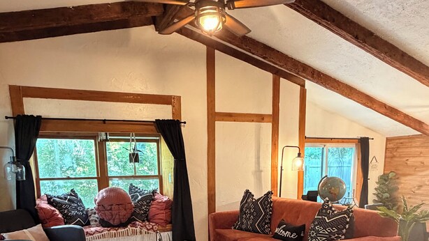 A cozy living room with a wooden ceiling, a sofa, a coffee table, and a view of the outdoors. - The Schoolhouse Cabin - 2BR, 1.5BA with Hot Tub and Game Room (Hudson)