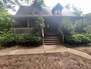 A two-story house with a front porch, a staircase leading to the entrance, and a well-maintained lawn.