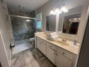 Un baño con cabina de ducha de vidrio, inodoro, lavabo con espejo y perchero para toallas.