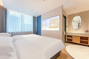 A hotel room with a bed, a large mirror, a TV screen, and a bathroom with a sink and vanity.