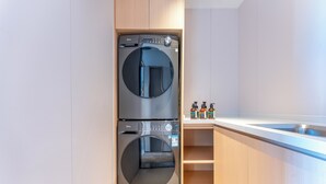 A compact kitchen with a built-in washer and dryer, a stainless steel sink, and a wooden countertop.