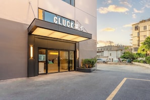 Un edificio moderno con un cartel que dice 'GLUCK' y un estacionamiento al frente.