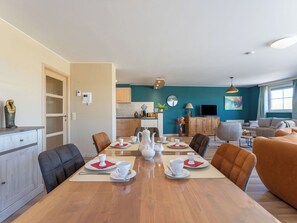 Ein modernes Wohnzimmer mit Essbereich, teal-farbenen Wänden und einem großen Fenster.