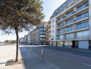 Ein mehrstöckiges Gebäude mit Balkonen, einem Fußweg und blauem Himmel.