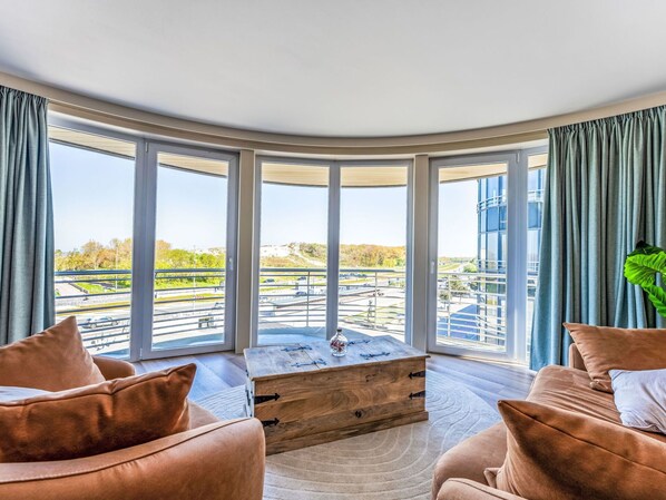 Ein Zimmer mit einer gewölbten Glasscheibe, einer hölzernen Kommode und zwei Sofas.