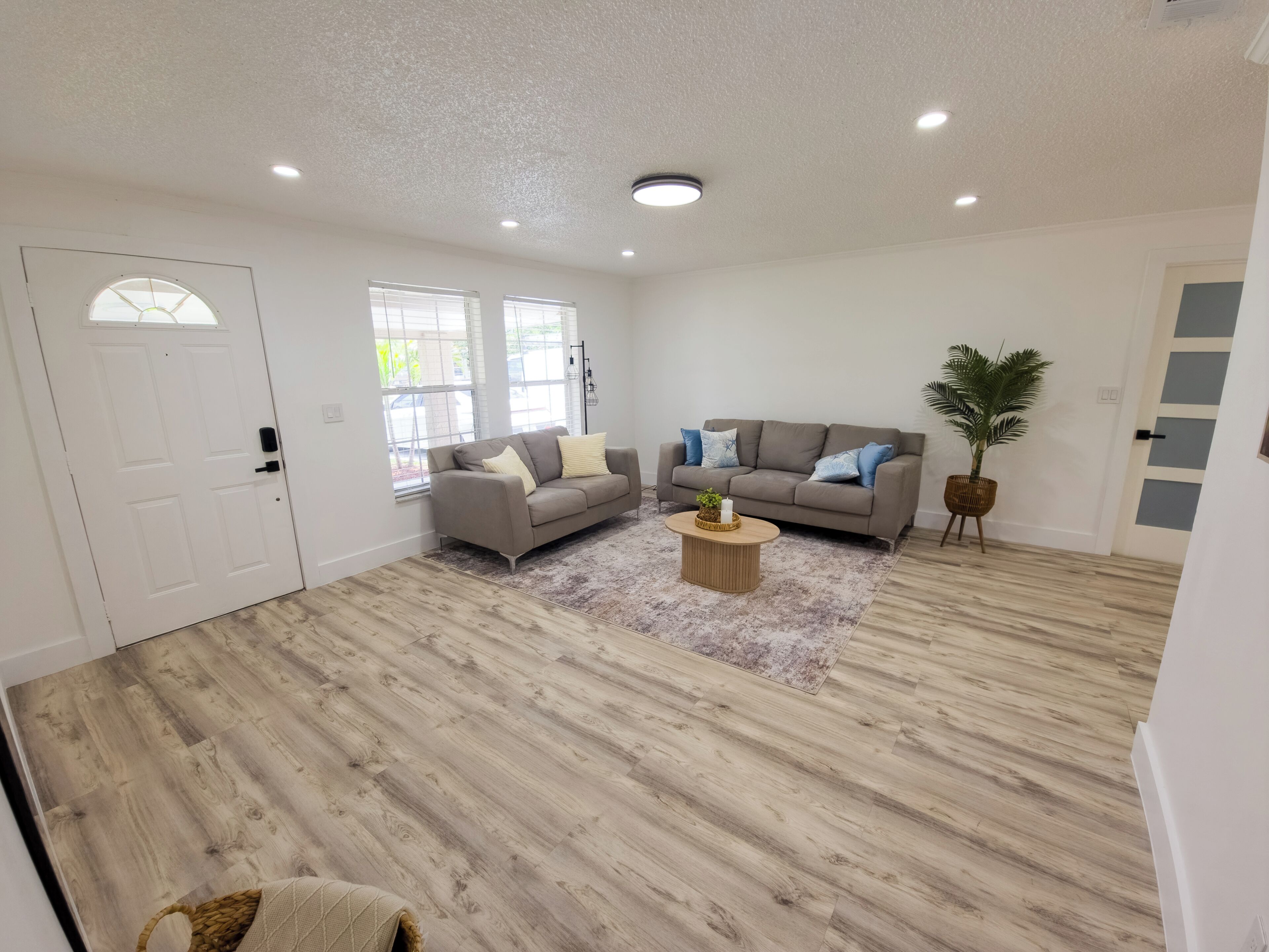 A spacious living area with a wooden floor, two sofas, a coffee table, and a door.