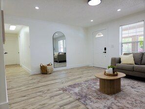 A spacious living room with a large mirror, a round wooden coffee table, and a gray sofa. - Velara Naples, Beautiful Family Pool Home Near Beach & Downtown. (Naples)