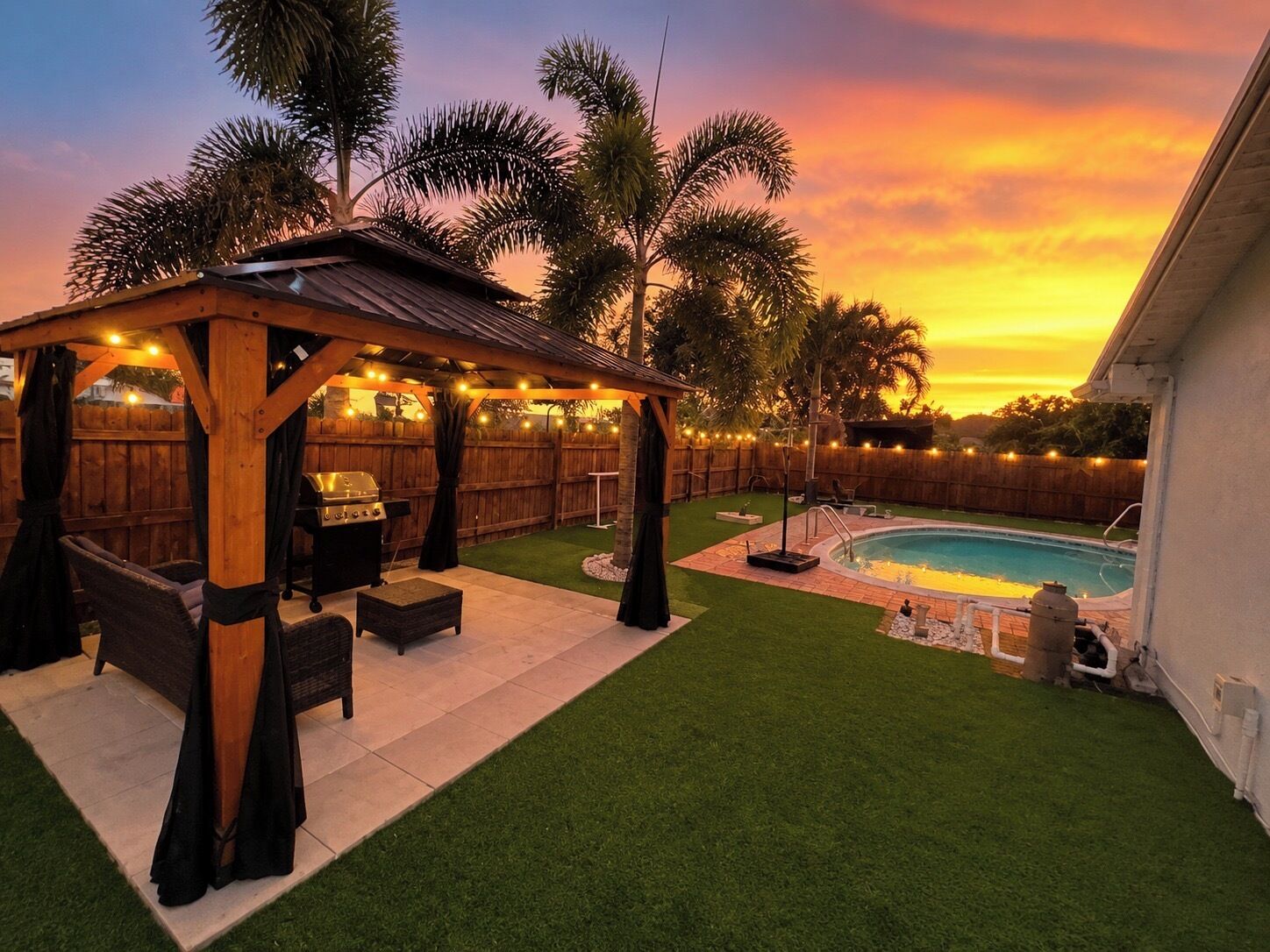 Un patio trasero con un porche de madera, una parrilla y una piscina.