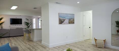 A modern living room with a sofa, a coffee table, a painting, and a kitchen area in the background.
