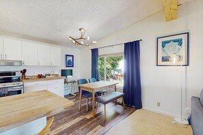 A modern kitchen with white cabinets, a wooden dining table, and a bench.