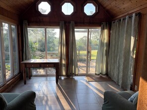 A room with a wooden ceiling, octagonal skylights, a table, two chairs, and large windows.