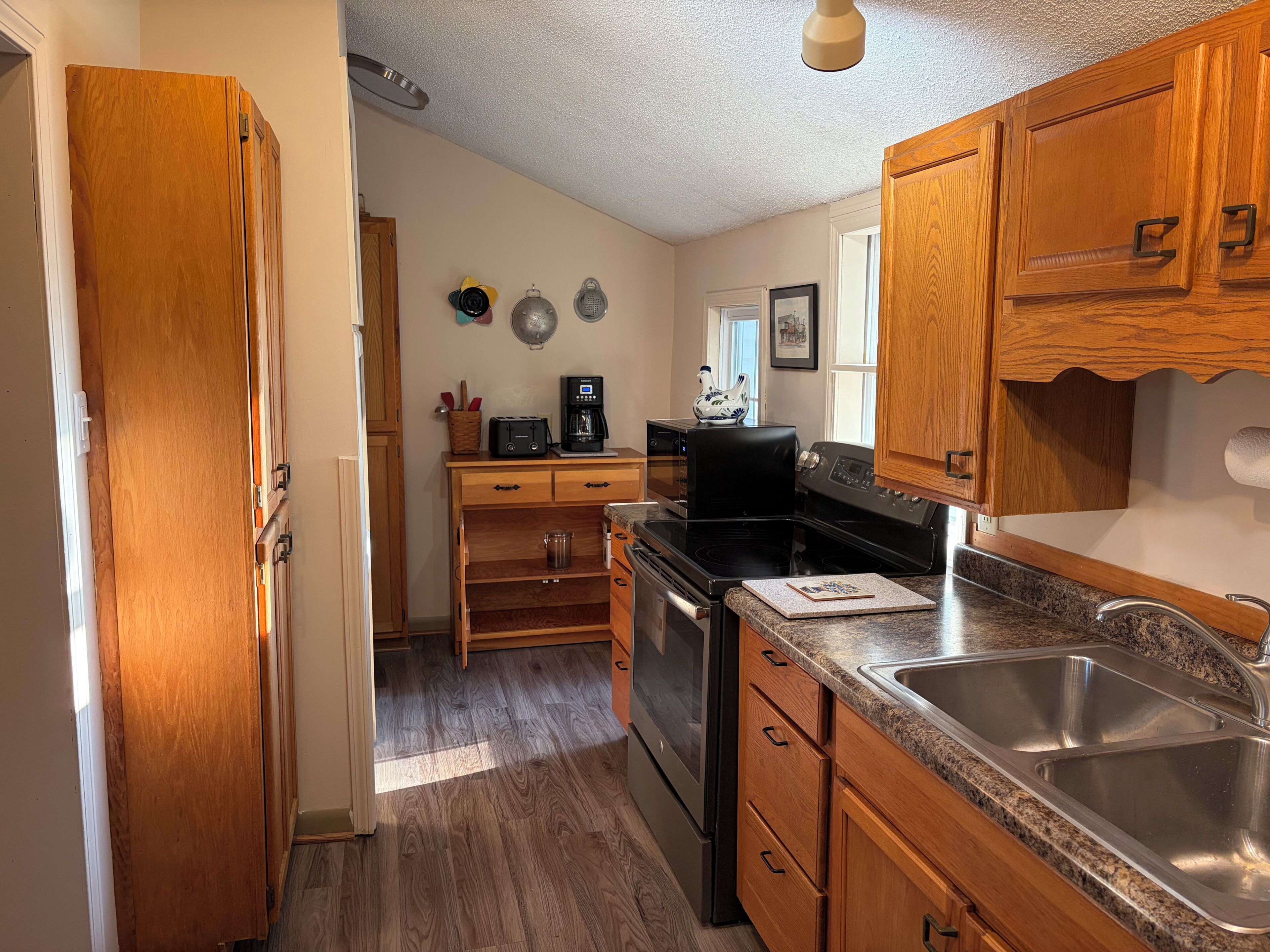 A kitchen with wooden cabinets, a stainless steel sink, a stove, and a microwave.