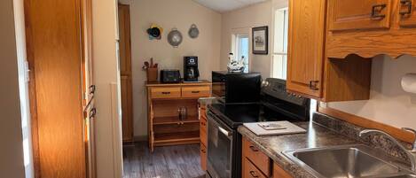 A kitchen with wooden cabinets, a stainless steel sink, a stove, and a microwave.