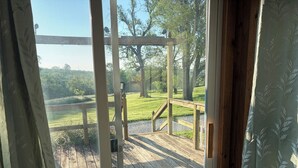 Eine Holzterrasse mit Geländer, Blick auf eine grüne Landschaft und einen klaren Himmel.