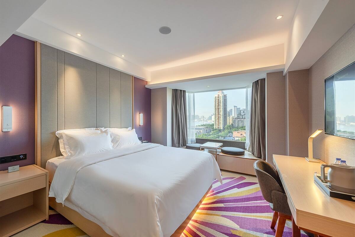 Una habitación de hotel con cama, escritorio y vista a la ciudad.