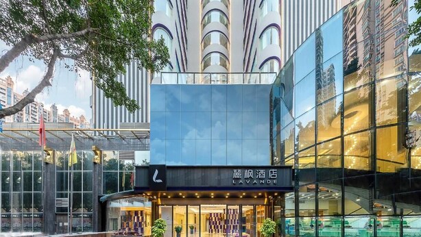A modern hotel with a glass facade, a prominent entrance, and a sign in a foreign language. - Lavande International Hotel Guangzhou Taigucang Shayuan Metro Station Branch - Free Shuttle Bus to Canton Fair Complex During Canton Fair Period (Guangzhou)