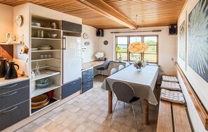 Uma cozinha moderna com armários embutidos, um espaço de refeições com mesa e cadeiras, e uma grande janela com vista.