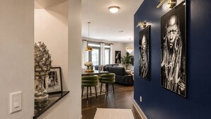 Un interior modern amb una paret d'accent blau fosc, una zona de menjador amb tamborets verds i obres d'art a les parets.
