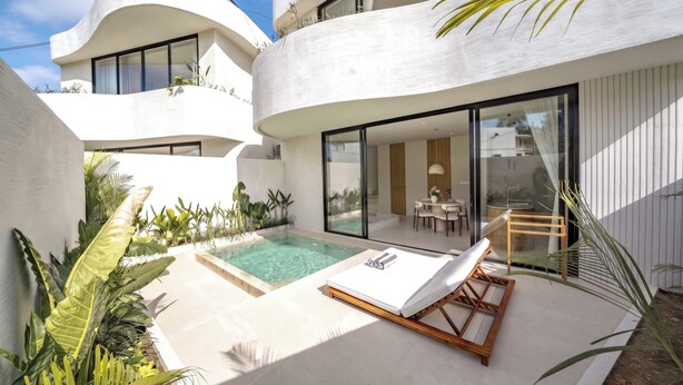 Una casa moderna con piscina, un área de descanso con una tumbona y un comedor.