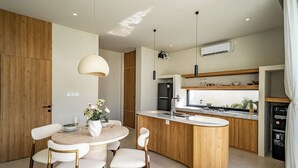 Una cocina moderna con una isla central, muebles de madera e iluminación colgante.