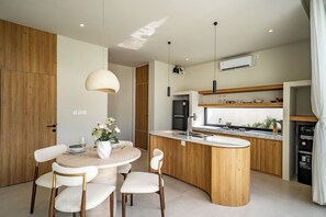 Uma cozinha moderna com ilha central, armários de madeira e iluminação pendente.