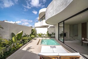 Un'area piscina moderna con vista aperta sul cielo, una piscina e un solarium con una sedia e un tavolo.