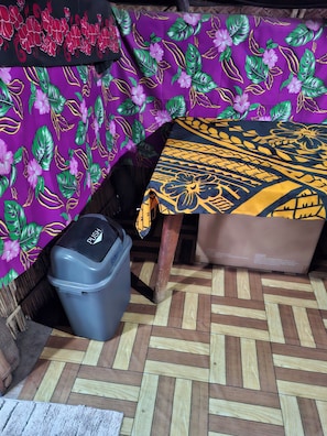 Une pièce avec une nappe à motifs, une poubelle et un parquet en bois à chevrons.
