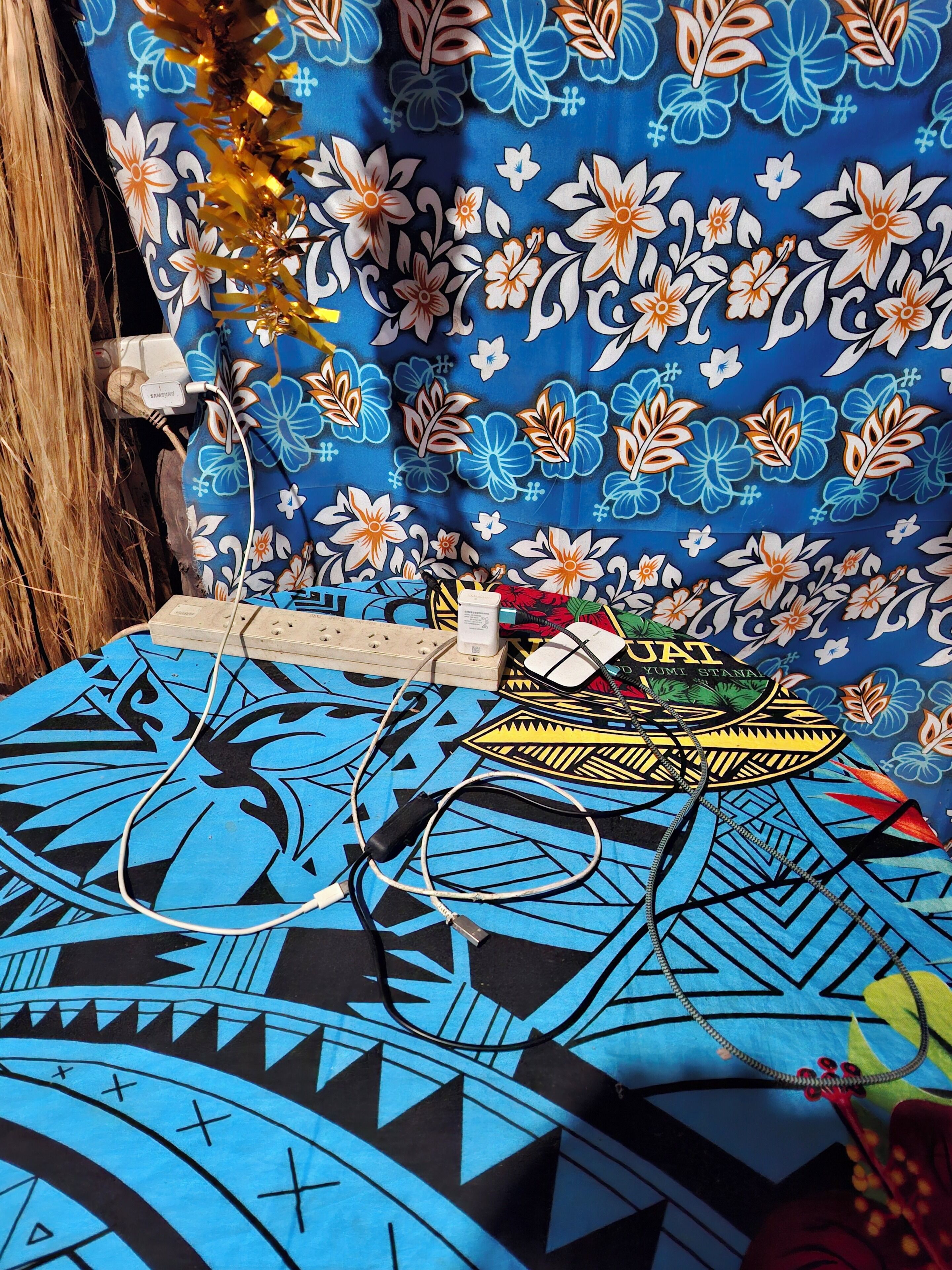 Una habitación con una pared azul y blanca estampada, una cama con diseño geométrico azul y negro, y un objeto decorativo sobre la cama.