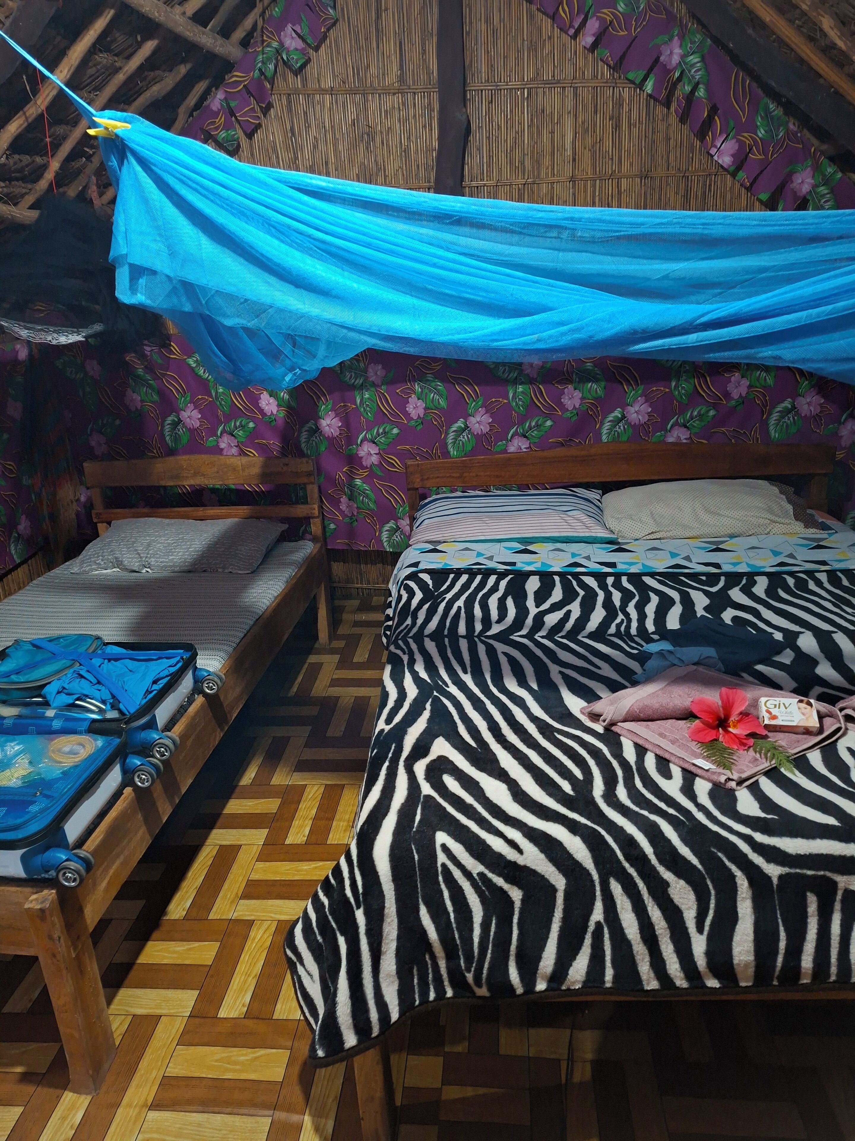 A room with two beds, one with a zebra-patterned bedspread and the other with a floral-patterned bedspread.