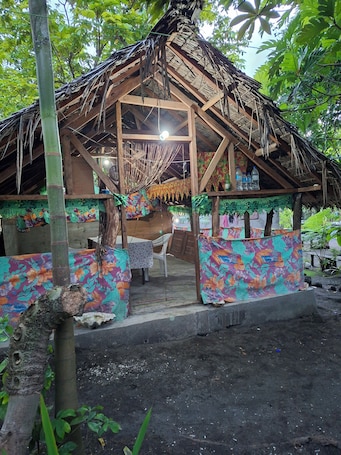 Eine rustikale Hütte mit einem Reetdach, Holzbalken und bunten floralen Mustern an den Wänden.. Tanna Chez Nous Bungalow and Tours