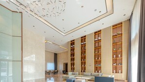 Un hall d’entrée spacieux avec un plafond haut, un espace salon central et une grande bibliothèque.