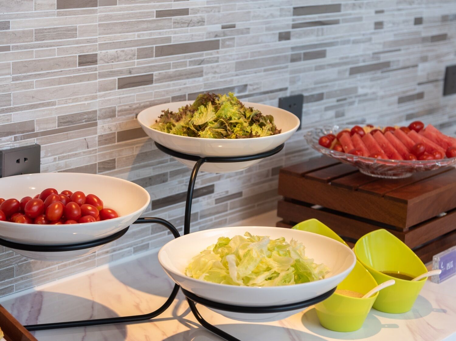 A buffet table with various food items including salads, tomatoes, and watermelon.