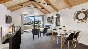 Un interior moderno con comedor, sofá, televisor y vistas a montañas.