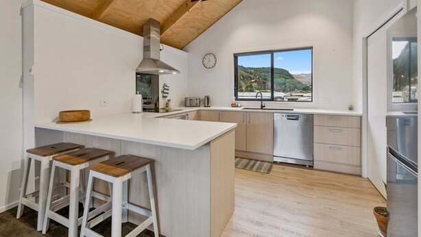 Una cocina moderna con una isla grande, taburetes de bar, electrodomésticos de acero inoxidable y vistas al exterior.